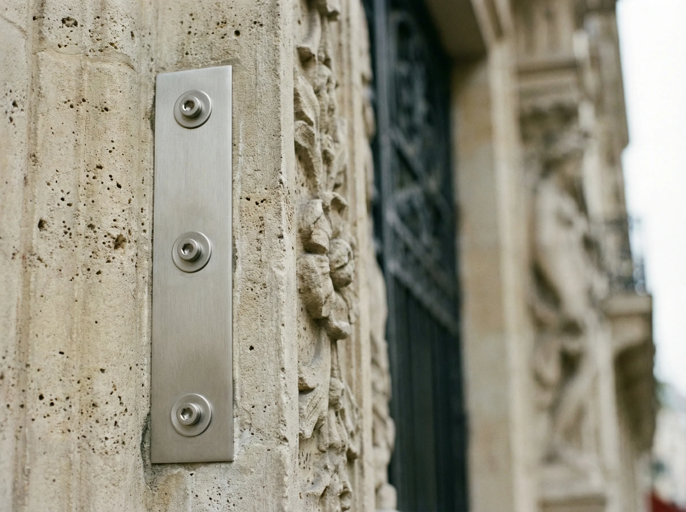Detail platine inox fixee sur pierre calcaire haussmannienne
